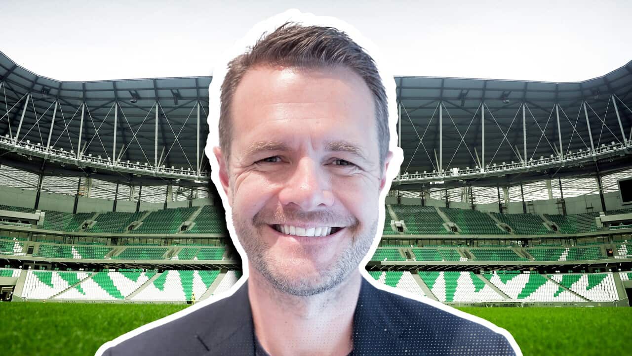 A man smiling with a football stadium in the background