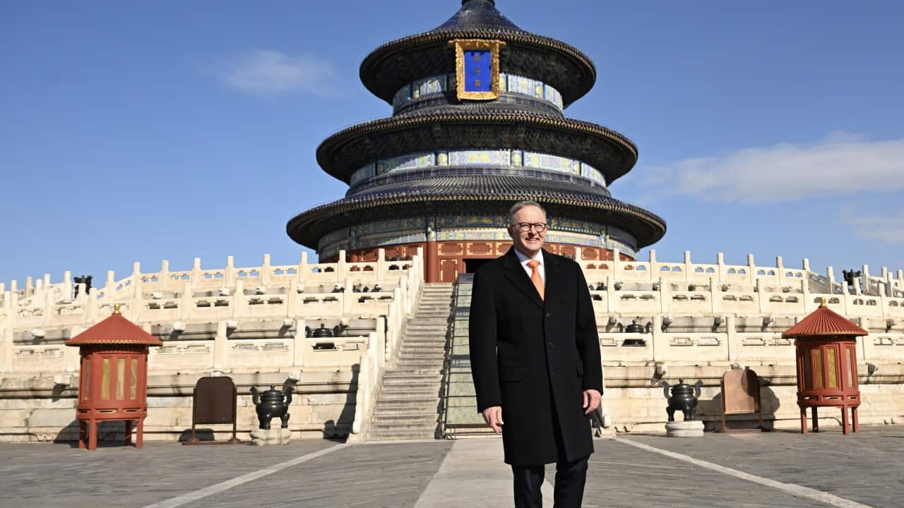 A man wearing a black coat in front of a Chinese temple