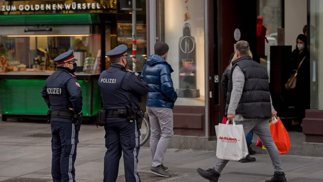 A man carries shopping bags as two police officers patrol streets during lockdown.