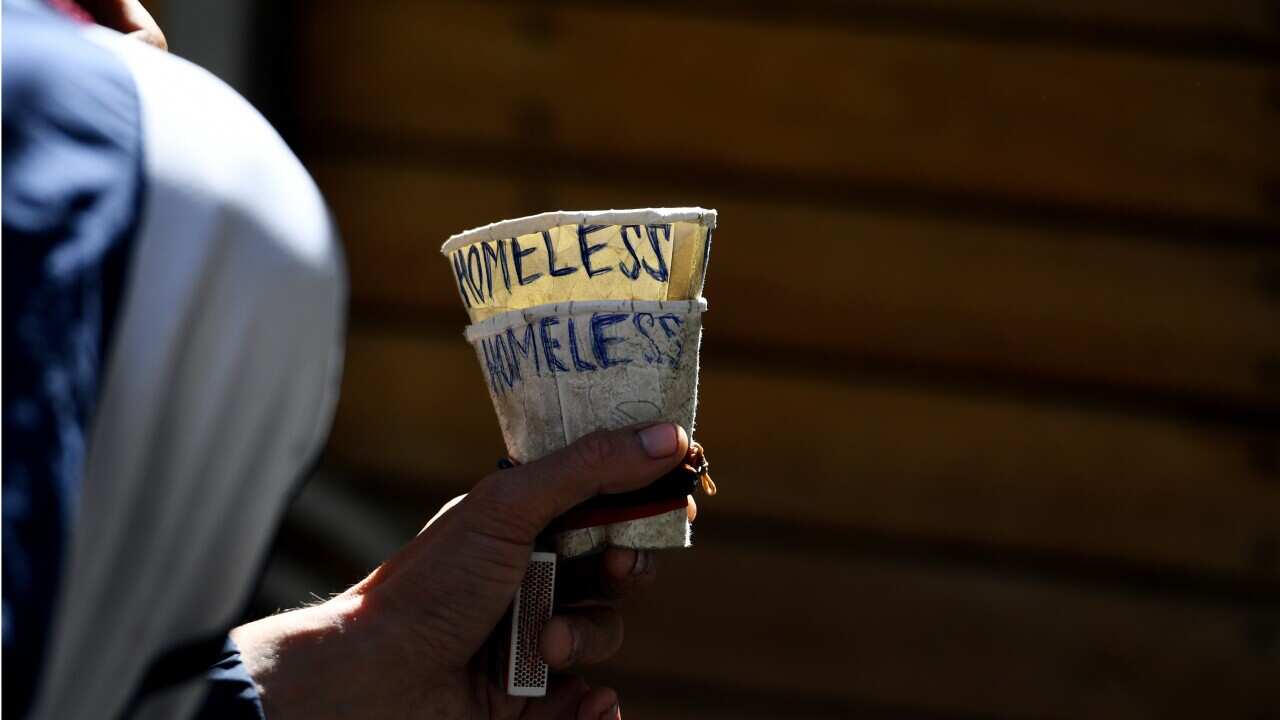 A homeless man holds a cup as he begs in Melbourne.