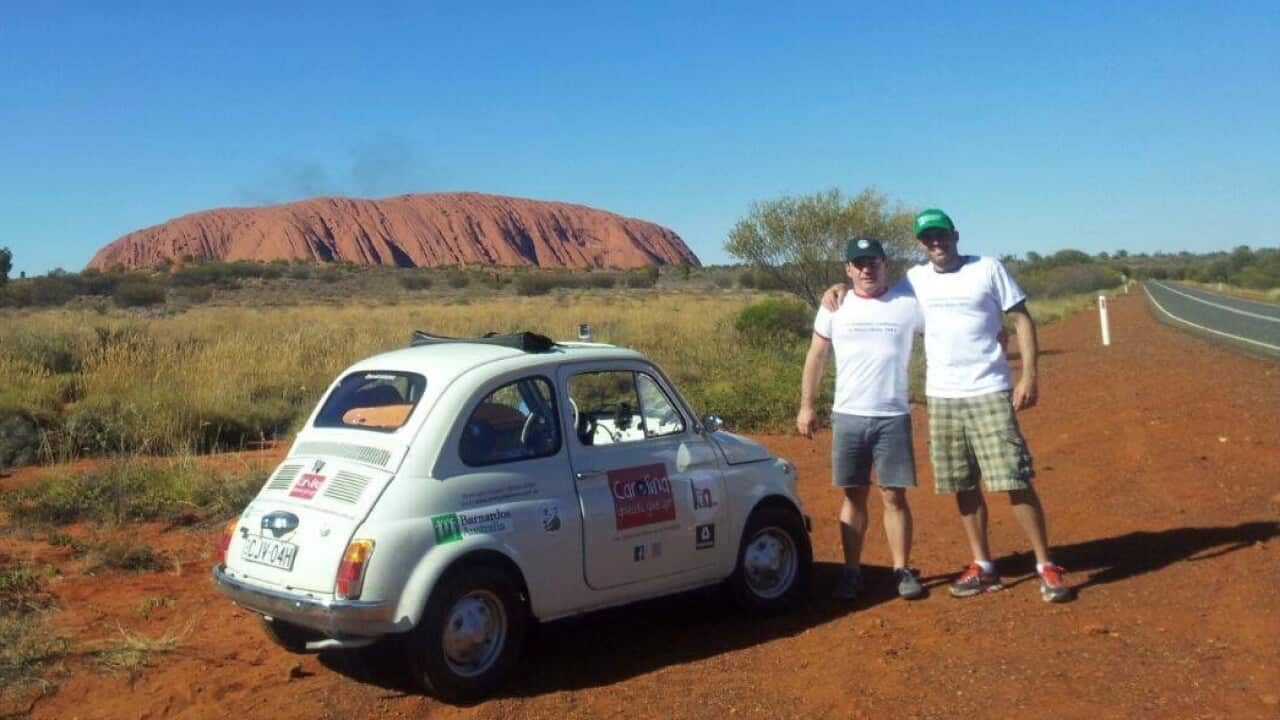 Roberto Mattei in front of Uluru with his Fiat 500 and his friend Simone.