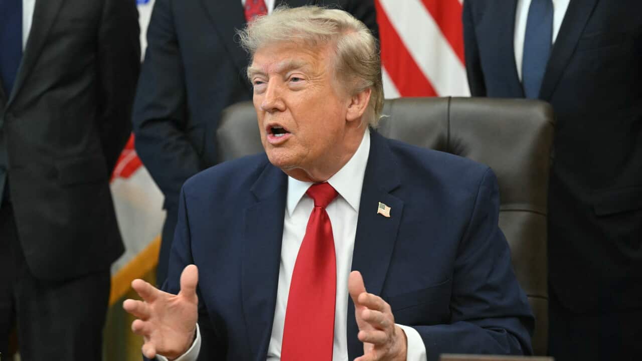 Donald Trump, sitting in a brown chair and waving his hands.
