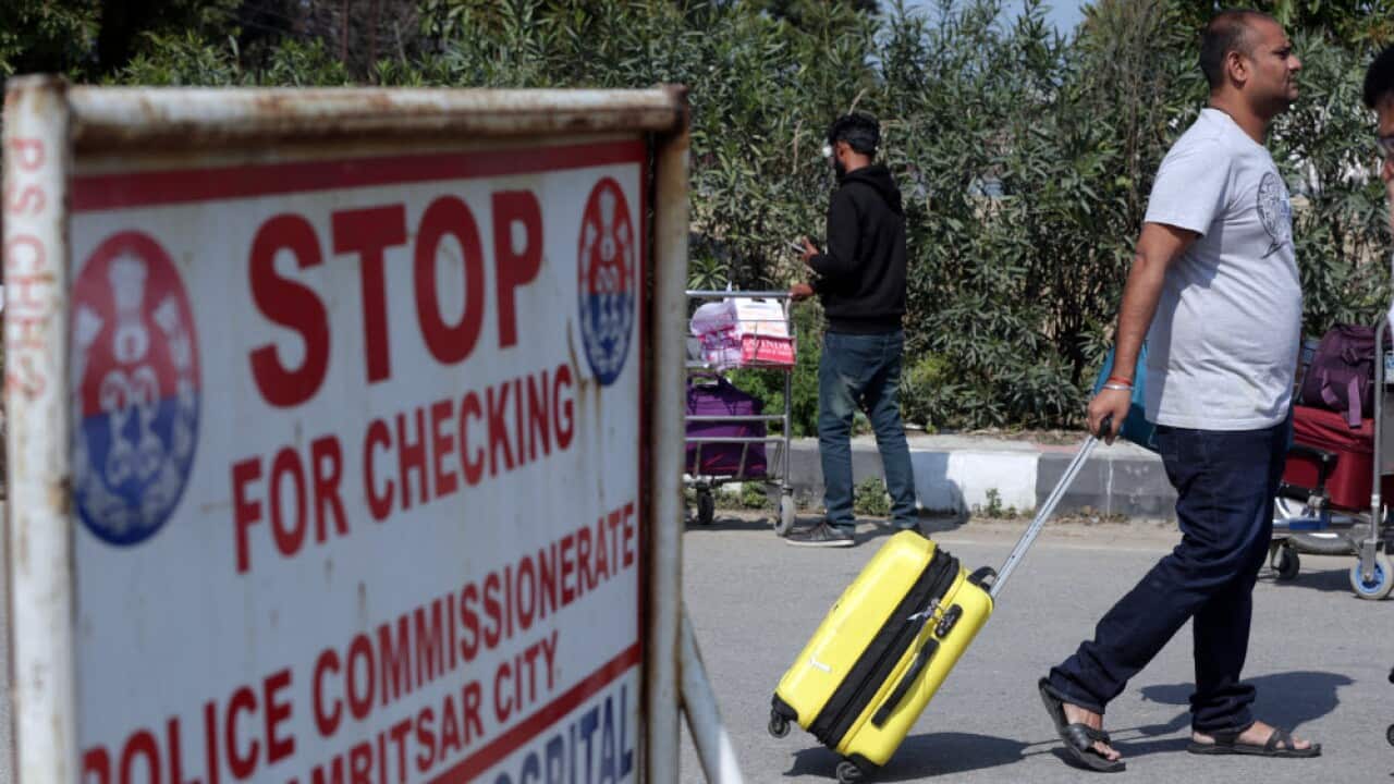 Stranded passengers walk with their belongings outside the Sri Guru Ramdas Ji International Airport