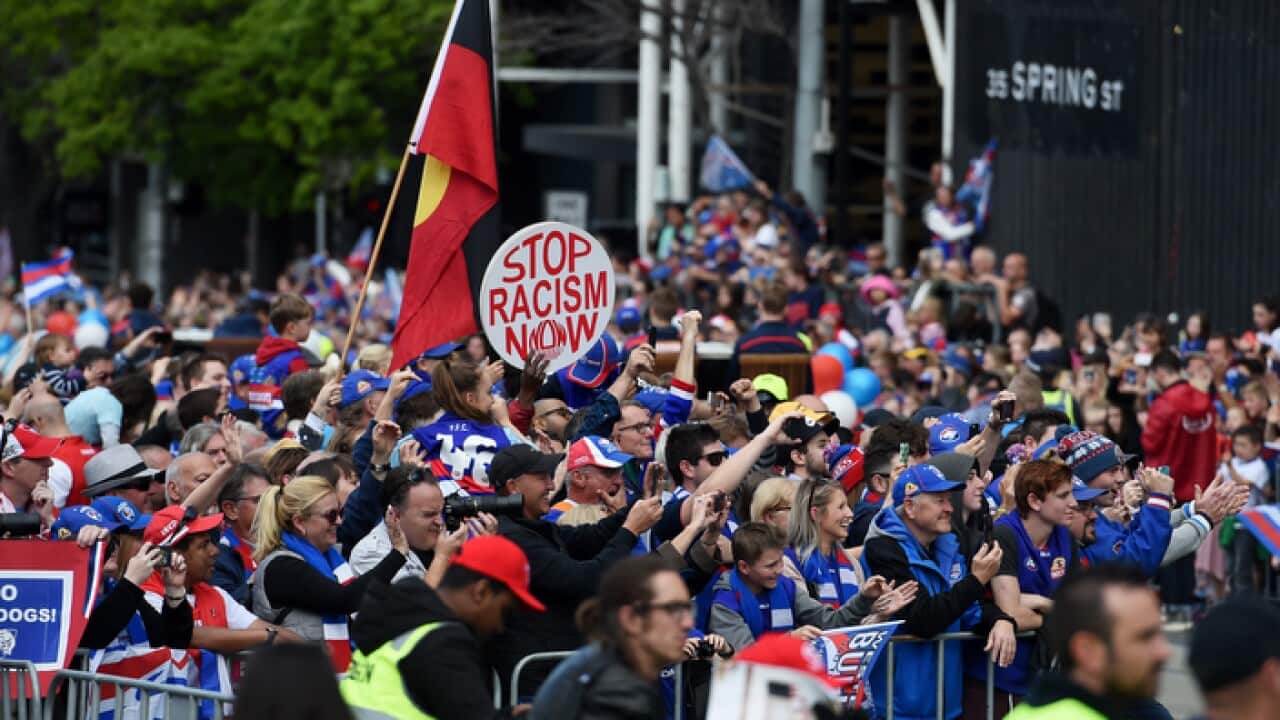 Protesters in support of Adam Goodes and against racism walk alongside the AFL Grand Final parade in Melbourne, Friday, Sept. 30, 2016. (AAP Image/Tracey Nearmy) NO ARCHIVING