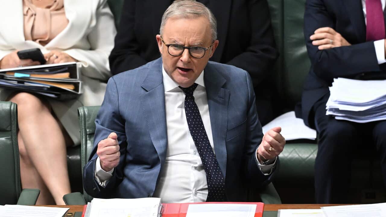 A man with grey hair clutching his fists.