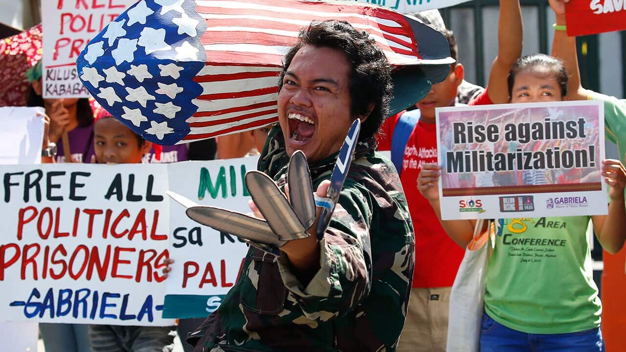 Protesters shout slogans while displaying placards during a rally outside the headquarters of the Philippine armed forces.