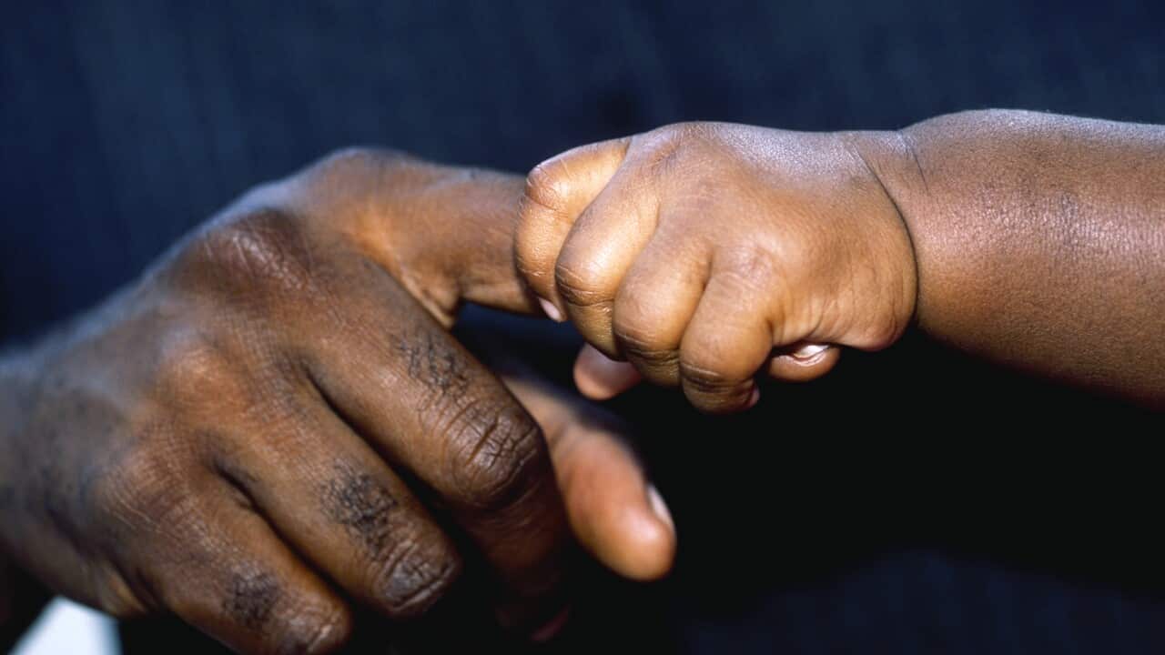 Baby gripping father's finger.