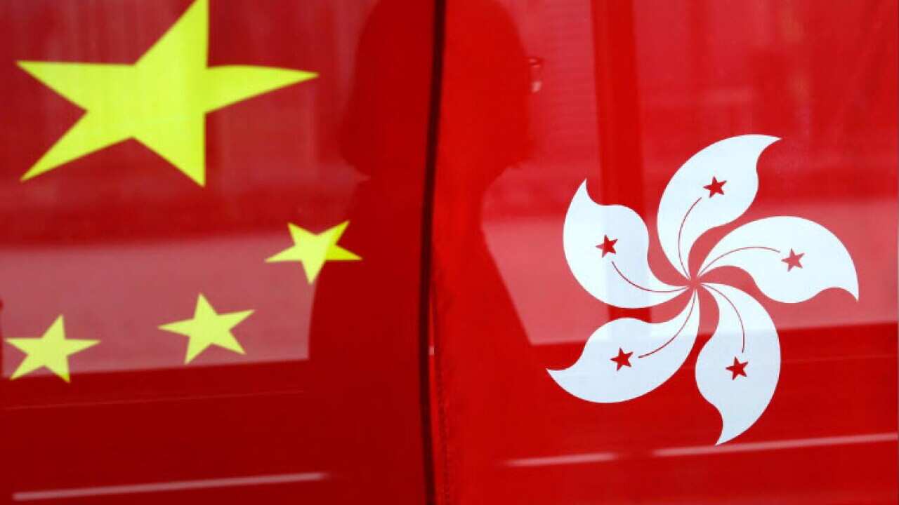 A woman is reflected in a window behind Chinese and Hong Kong flags after celebrations commemorating the 20th anniversary of Hong Kong's handover to Chinese sovereignty from British rule, in Hong Kong, China July 2, 2017. REUTERS/Tyrone SiuTyrone Siu
