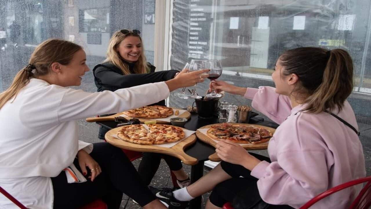 Women clink glasses a restaurant in Sydney.