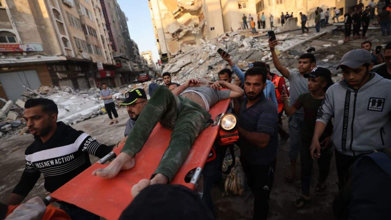 Palestinians carry a survivor found under the rubble of a building after it was struck by Israeli strikes in Gaza City, May 16, 2021