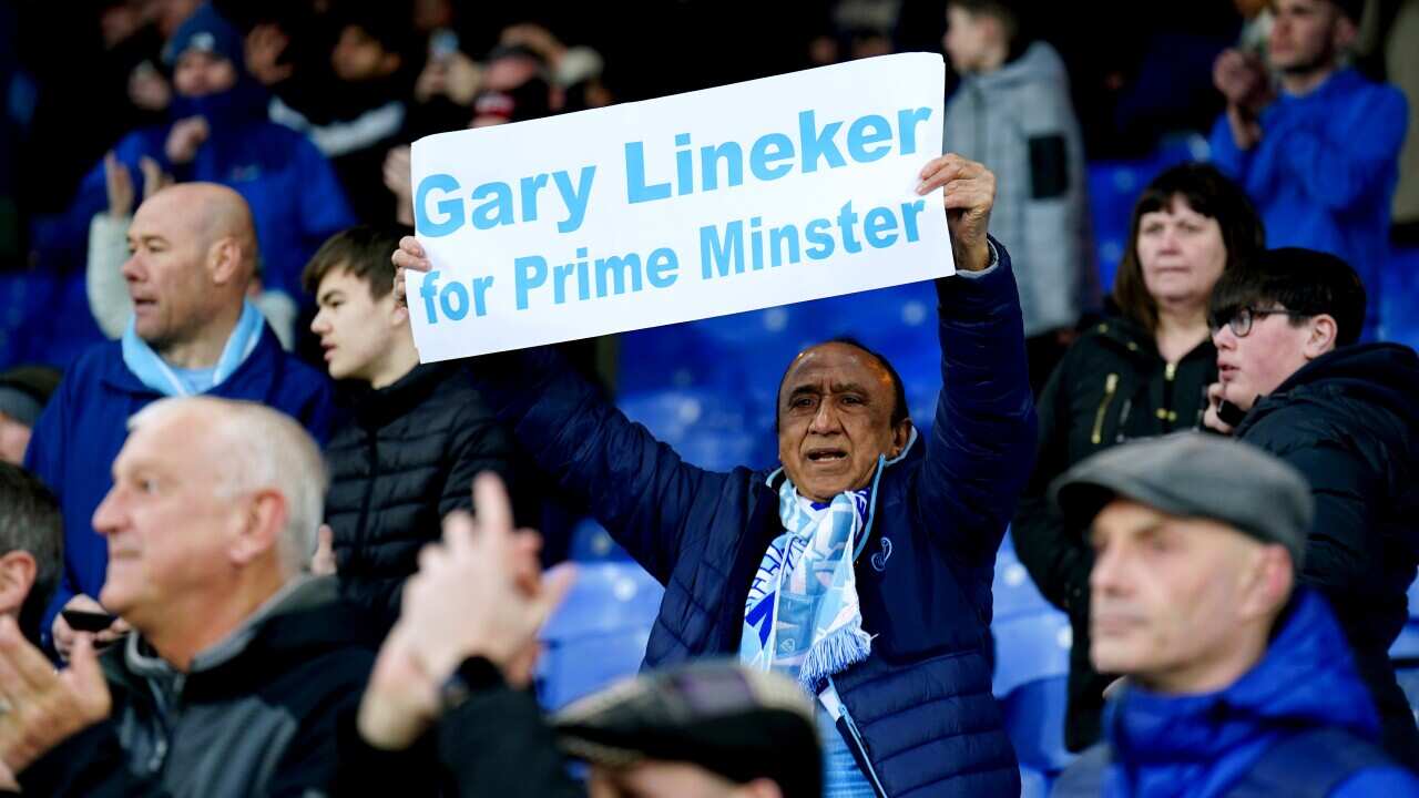 A man holds a sign that reads: "Gary Lineker for prime minister" at a football game.