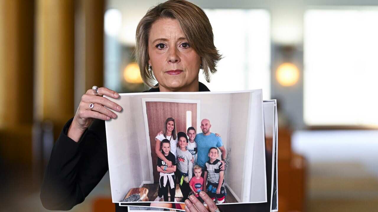 Shadow Immigration Minister Kristina Keneally holds up pictures of stranded Australian citizens during a press conference at Parliament House in Canberra, Thursday, September 24, 2020. (AAP Image/Lukas Coch) NO ARCHIVING