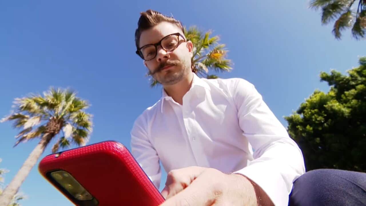 Low angle shot of a man; sitting outside looking at his mobile phone.