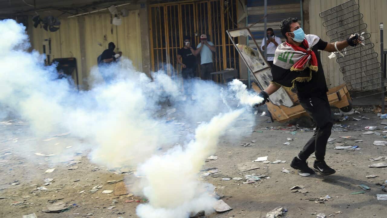 An anti-government protester prepares to throw back a tear gas canister fired by police during clashes at Khilani Square in Baghdad, Iraq, Thursday, Nov. 14, 2019. (AP Photo/Hadi Mizban)