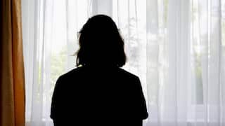 A woman's silhouette as she looks out a window.