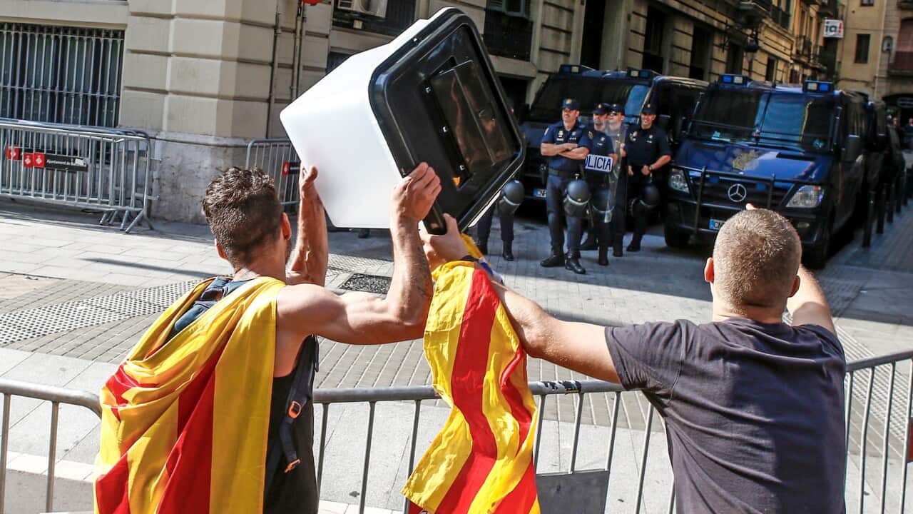  A demonstrator holds a ballot box in front of police officers during a protest against the decision by the Spanish Supreme Court.