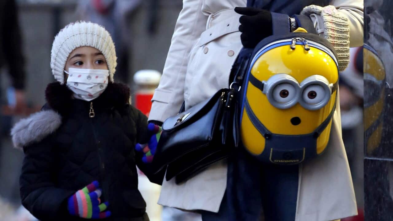 An Iranian woman and her child wearing face masks walk on a street of Tehran, Iran, 22 February 2020.
