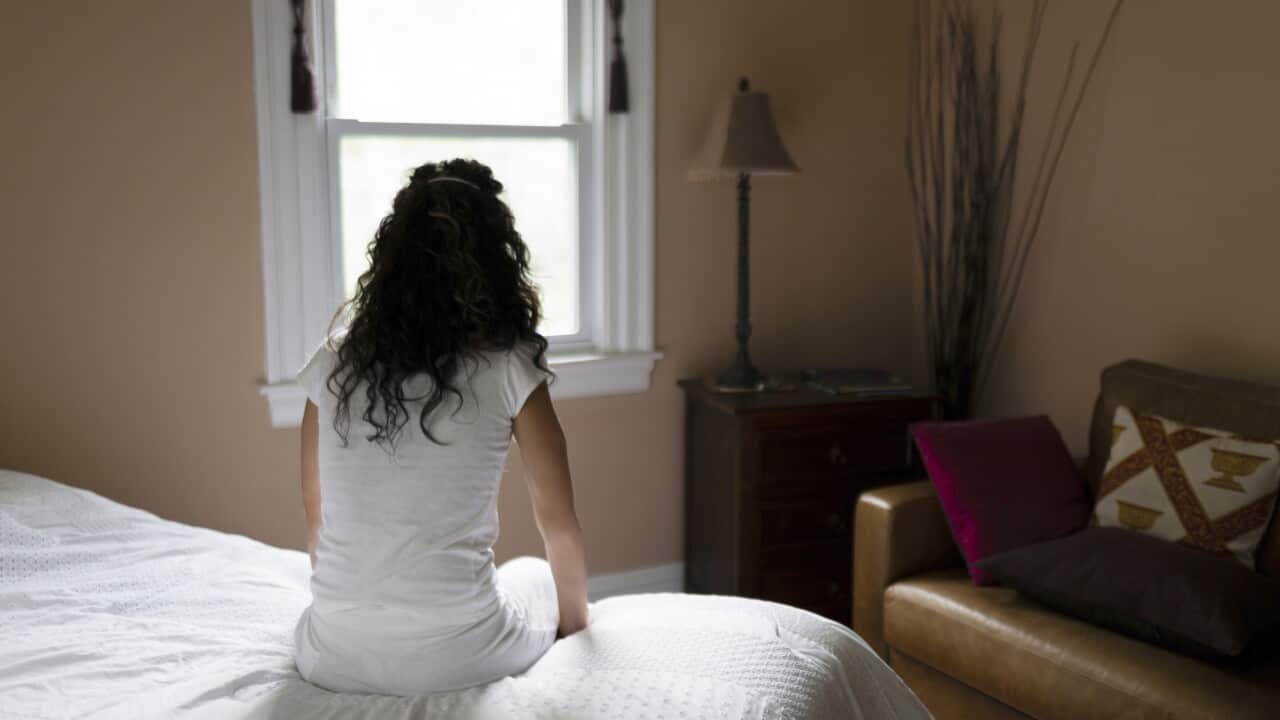 Woman sitting on edge of bed