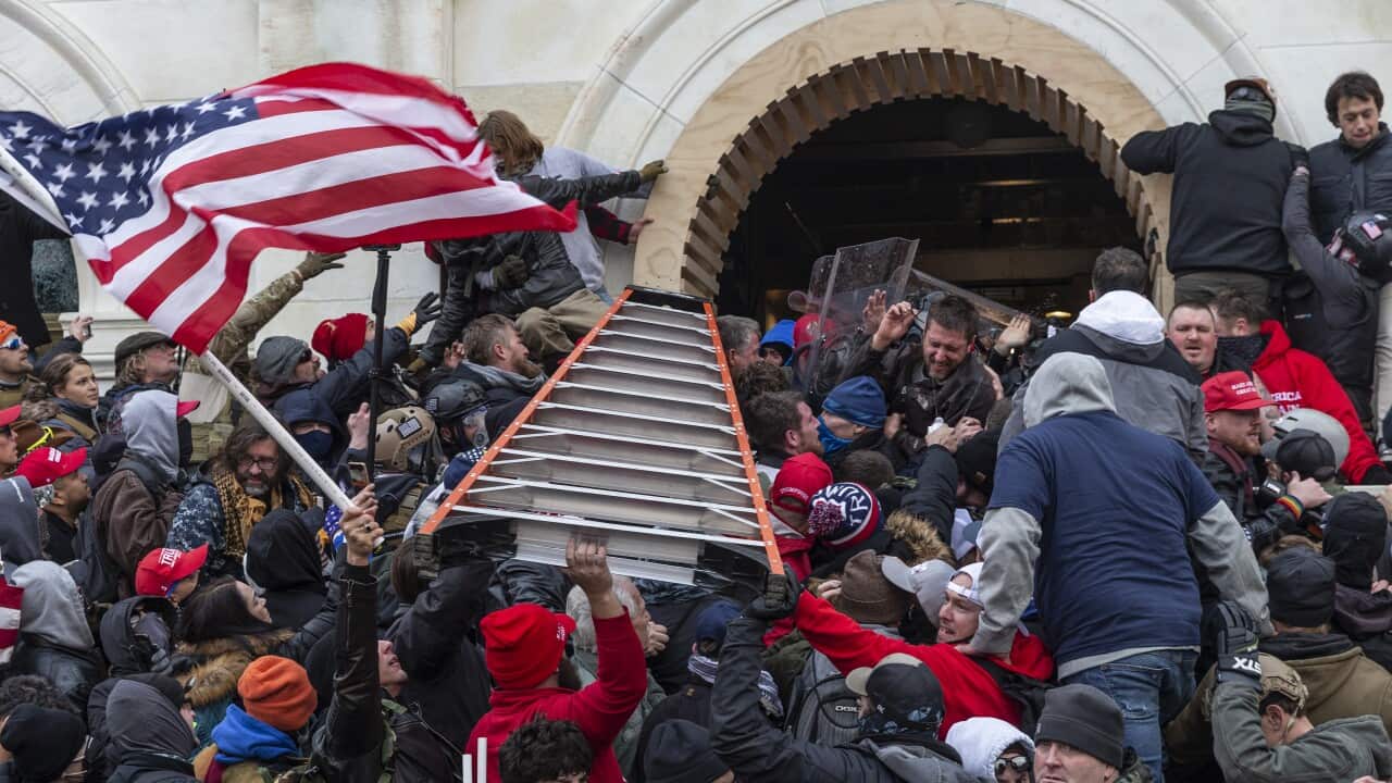 Rioters clash with police using a ladder trying to enter the Capitol building through the front doors in Washington, DC on 6 January, 2021.