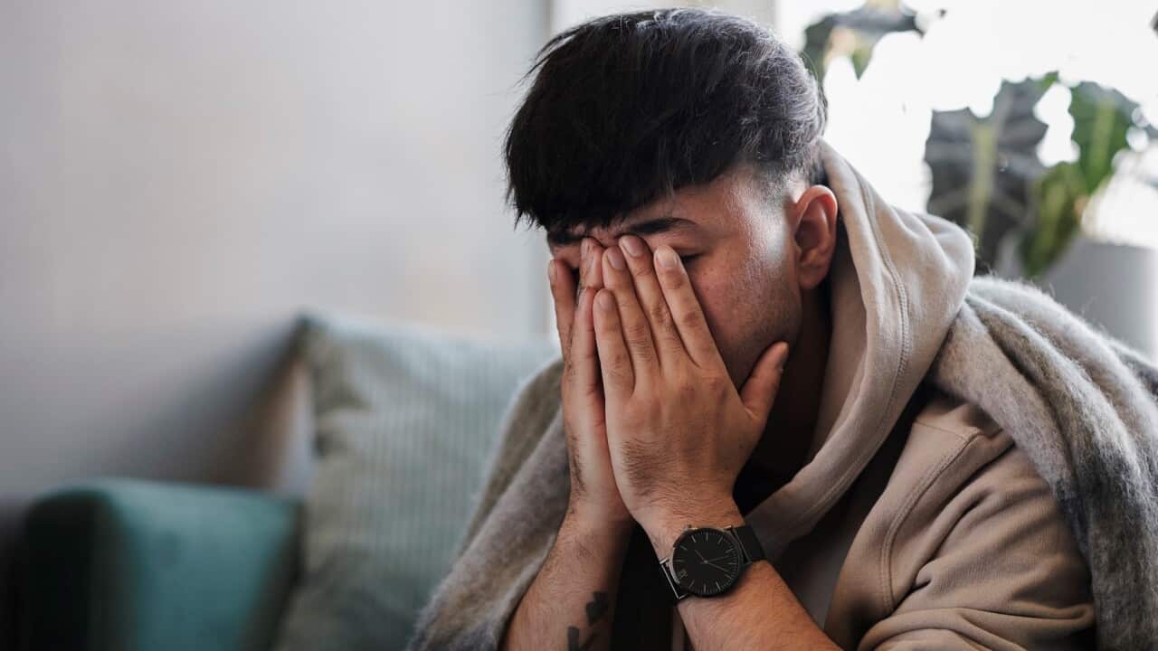 Ill man on sofa with hands covering face