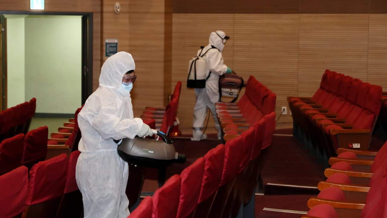Health workers disinfect the main auditorium at the parliamentary member's office building in the National Assembly in Seoul, South Korea, 24 February 2020.