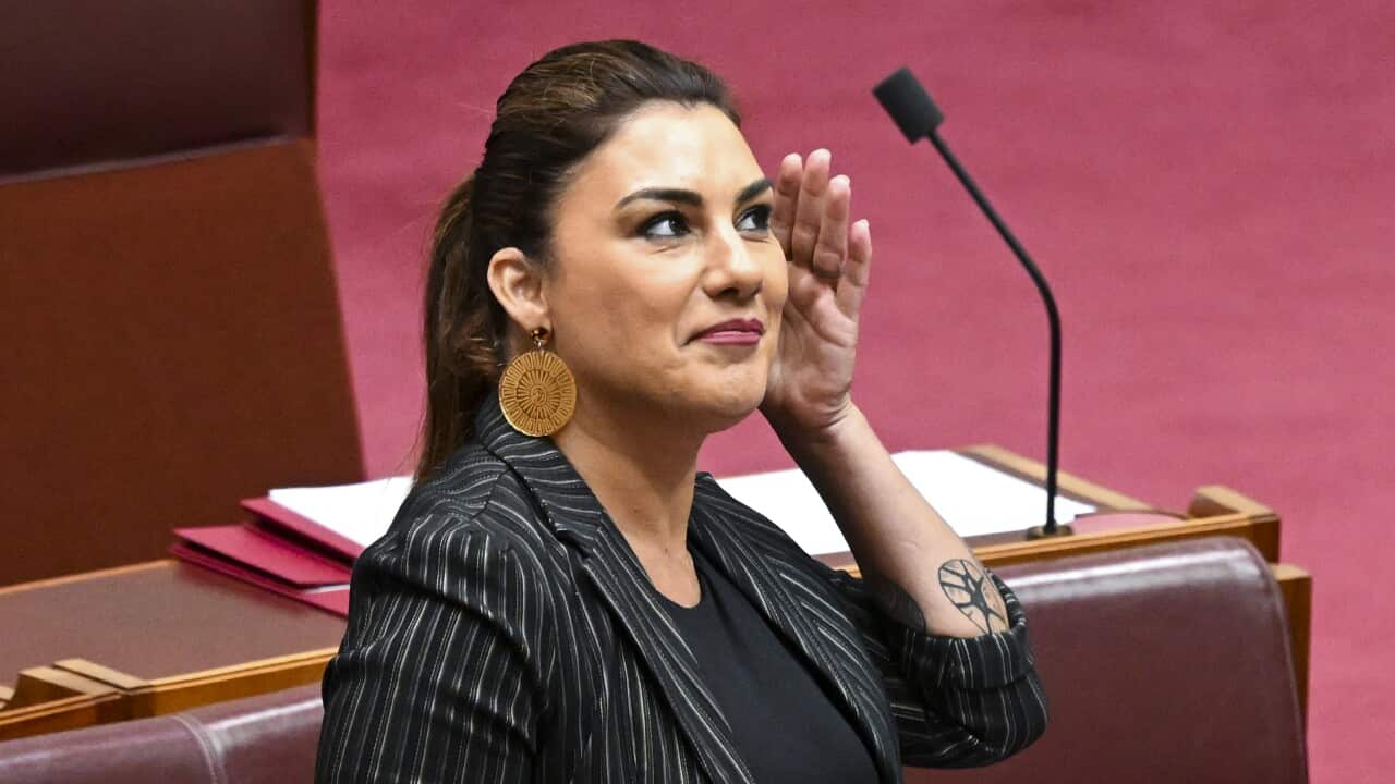 Lidia Thorpe puts her hand to her left ear as she speaks in the Senate chamber