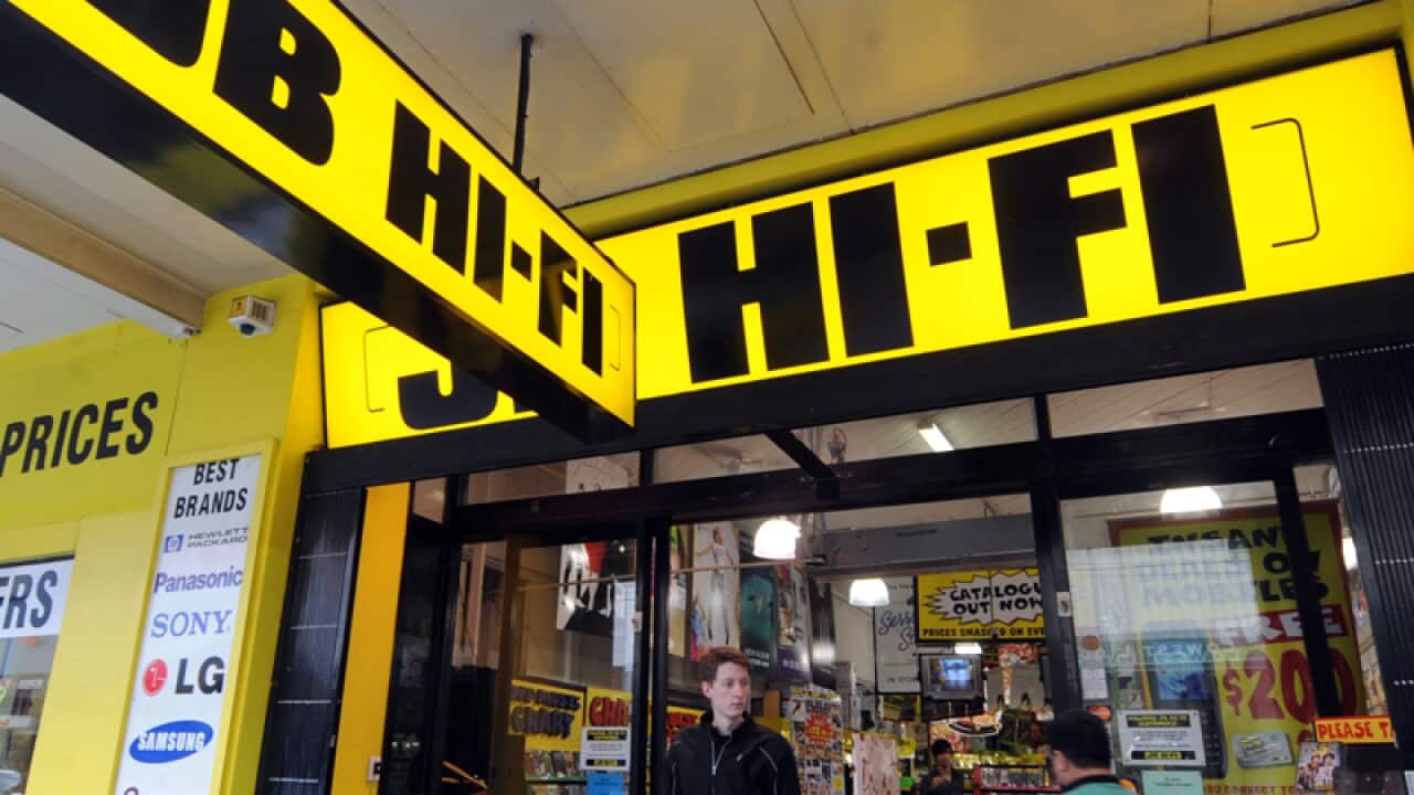 Pedestrains walk past a JB HI-FI store in Melbourne