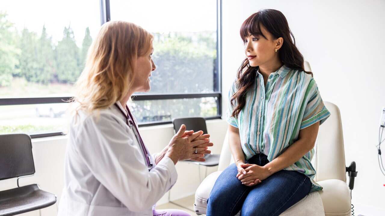 Female doctor talking with young woman in exam room