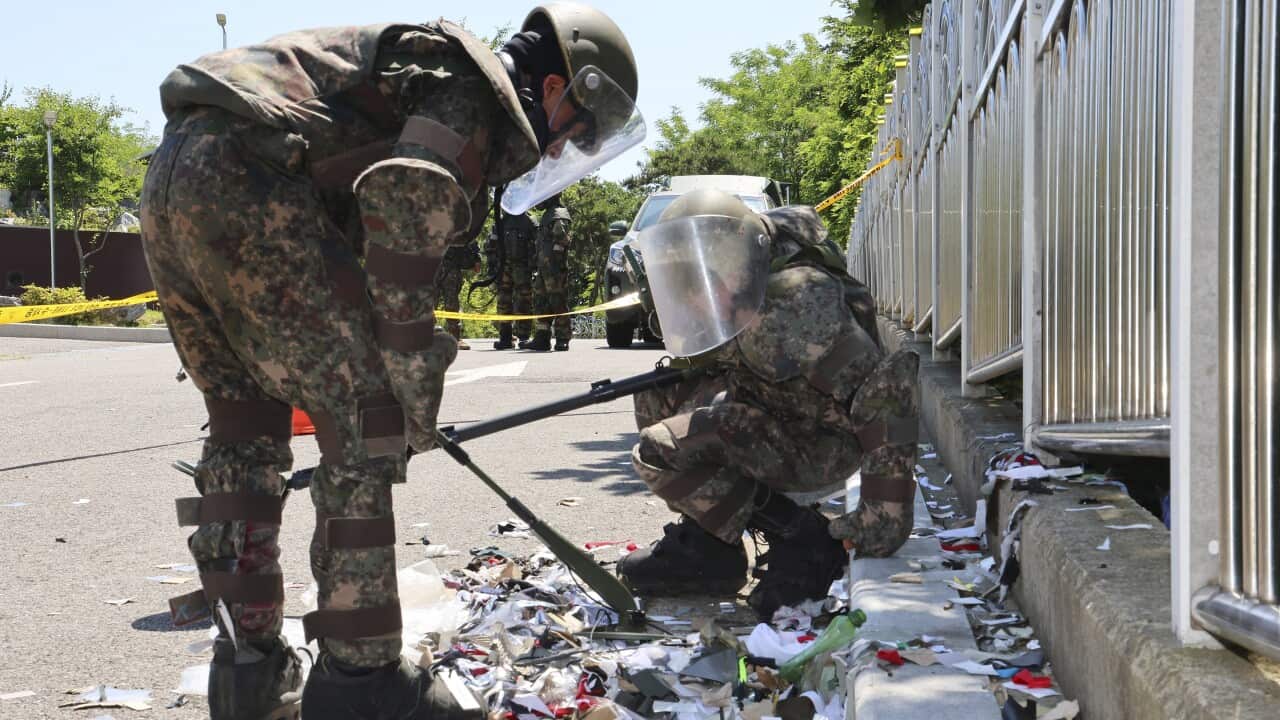 Soldiers wearing protective gears check the trash from a balloon.