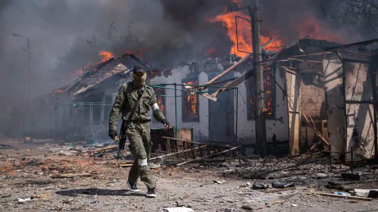 A serviceman of the Lugansk People's Republic military in a burning market in the town of Popasnaya, Ukraine.