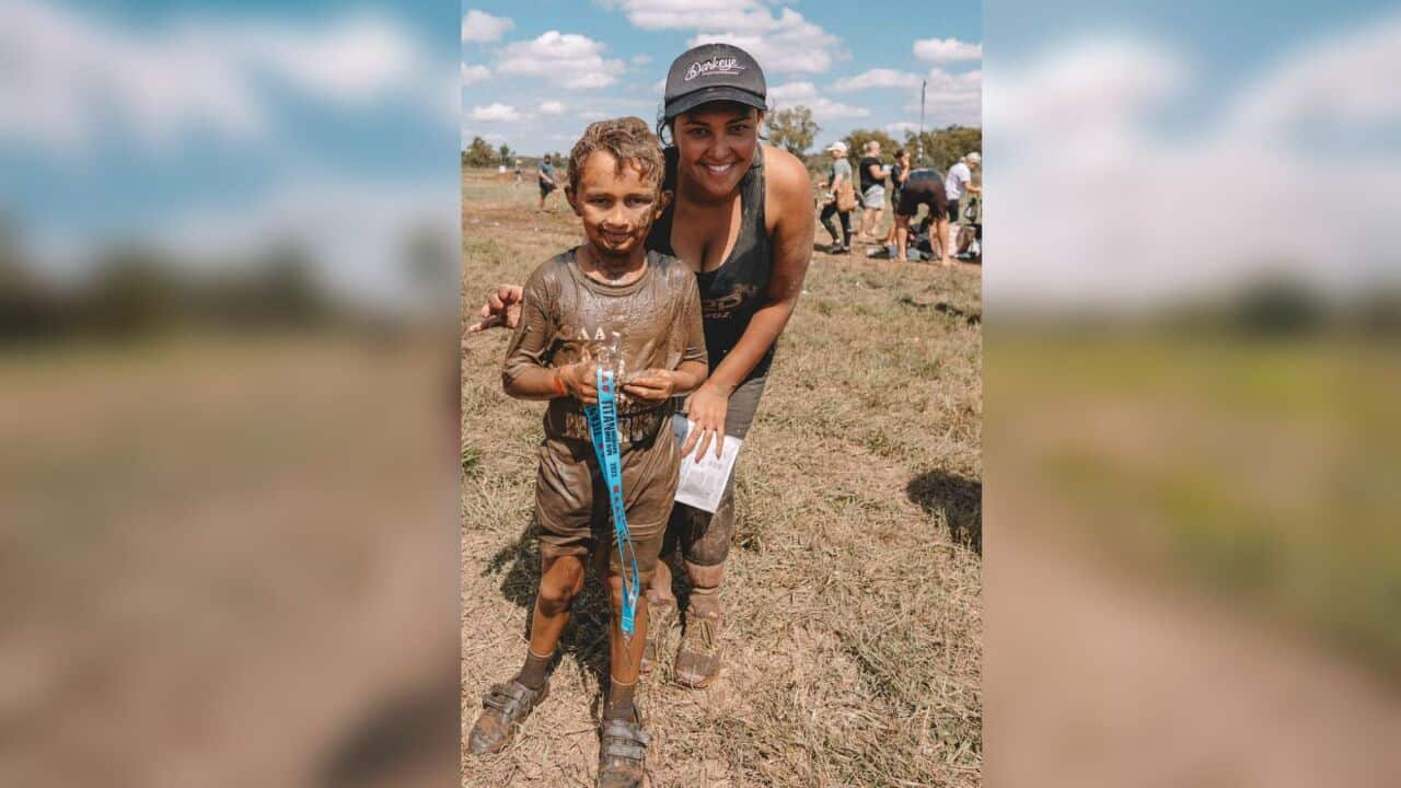 A woman is seen smiling with her child at a tough mudders event.