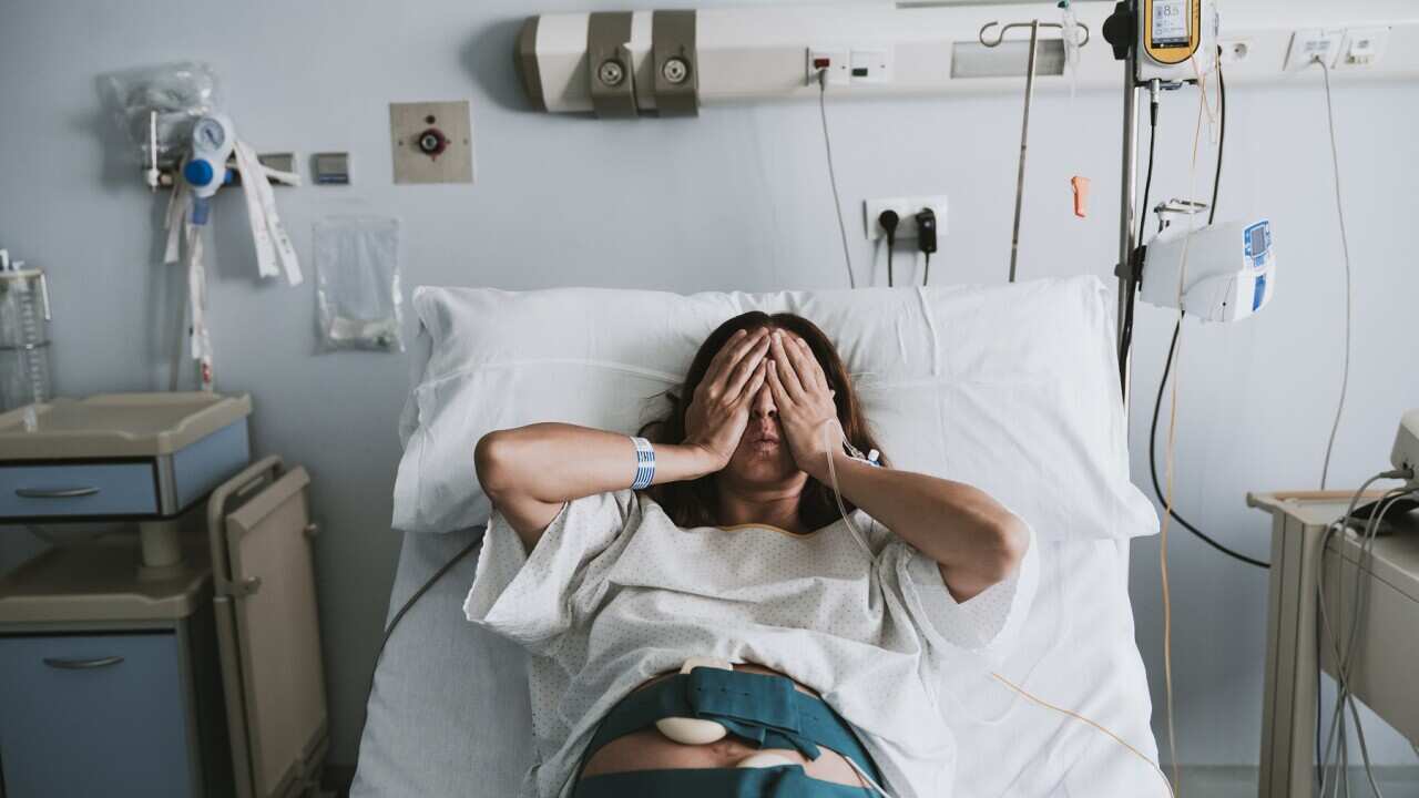 Stressed pregnant woman lying on bed in hospital