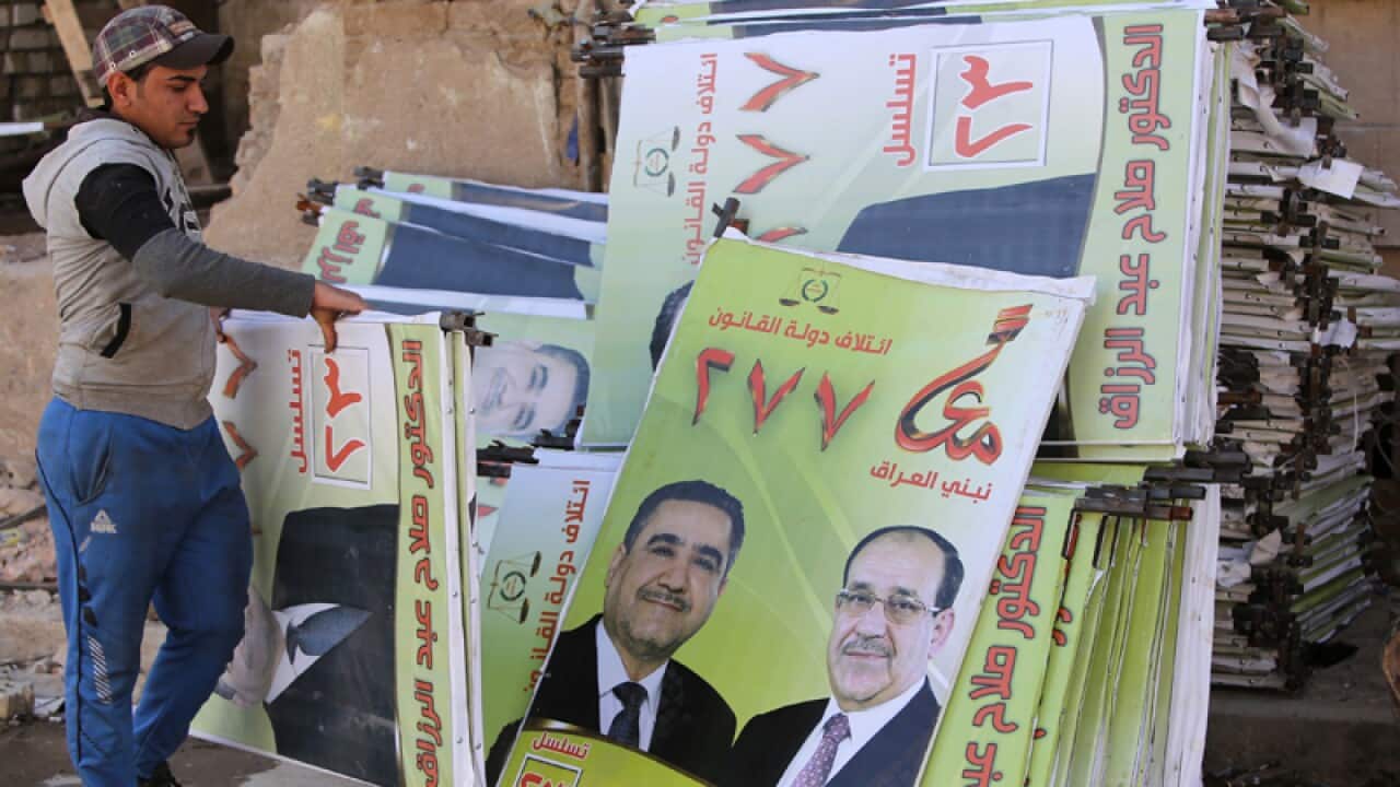 An Iraqi employees puts together campaign posters