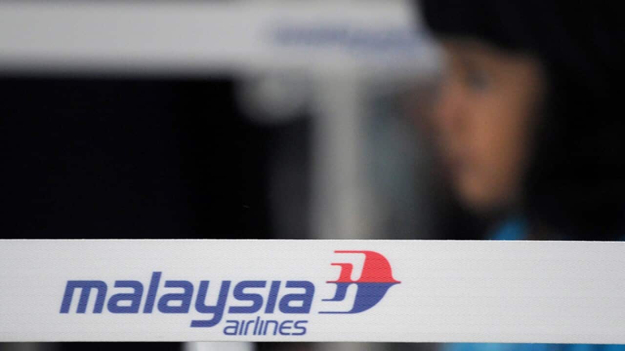 A girl walks past a Malaysian Airlines logo in Kuala Lumpur