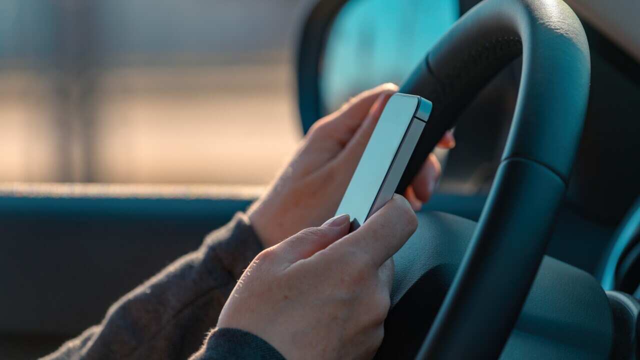 Businesswoman driving car and text messaging on mobile phone