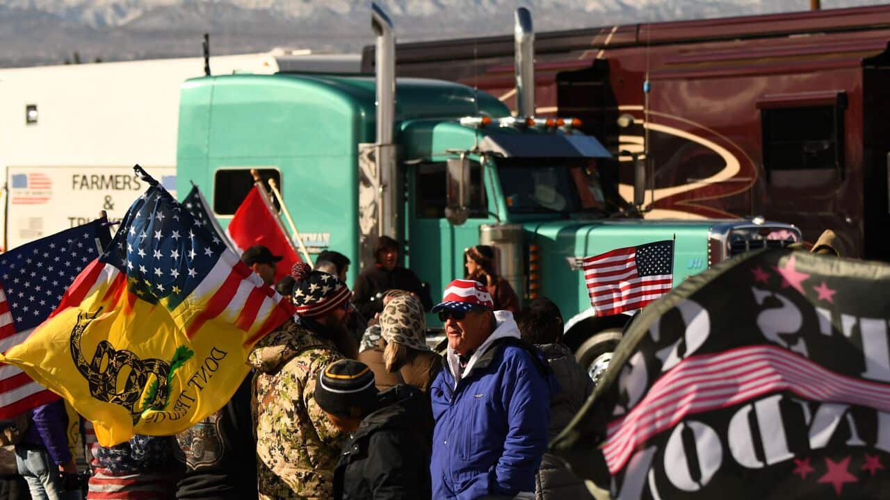 People standing in front of a truck are seen holding flags.