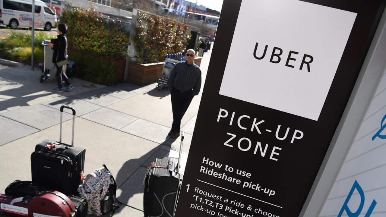 Travellers wait at the new designated pick-up zone for Uber at Tullamarine Airport in Melbourne.