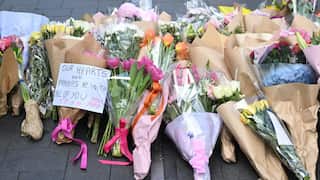 Bunches of floral tributes with a note that reads, "Our hearts and prayers are with all of you".