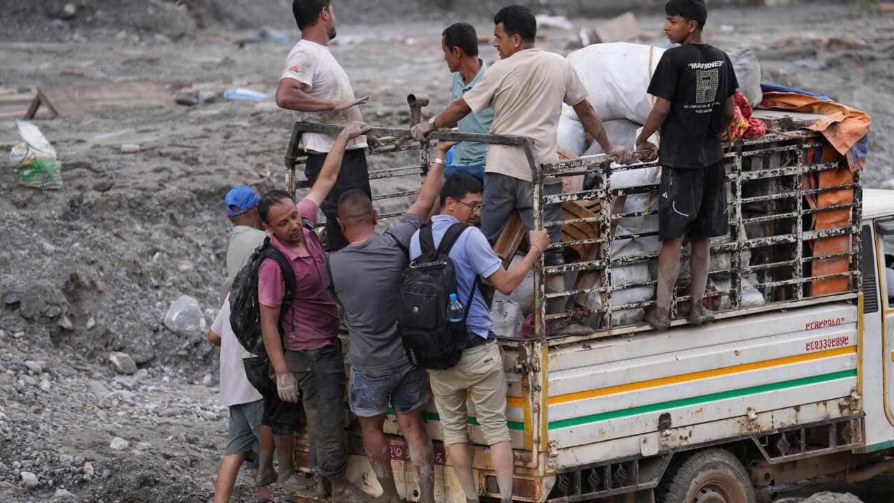Flood affected people stand atop a mini truck carrying salvaged goods from their damaged dwellings (AAP)