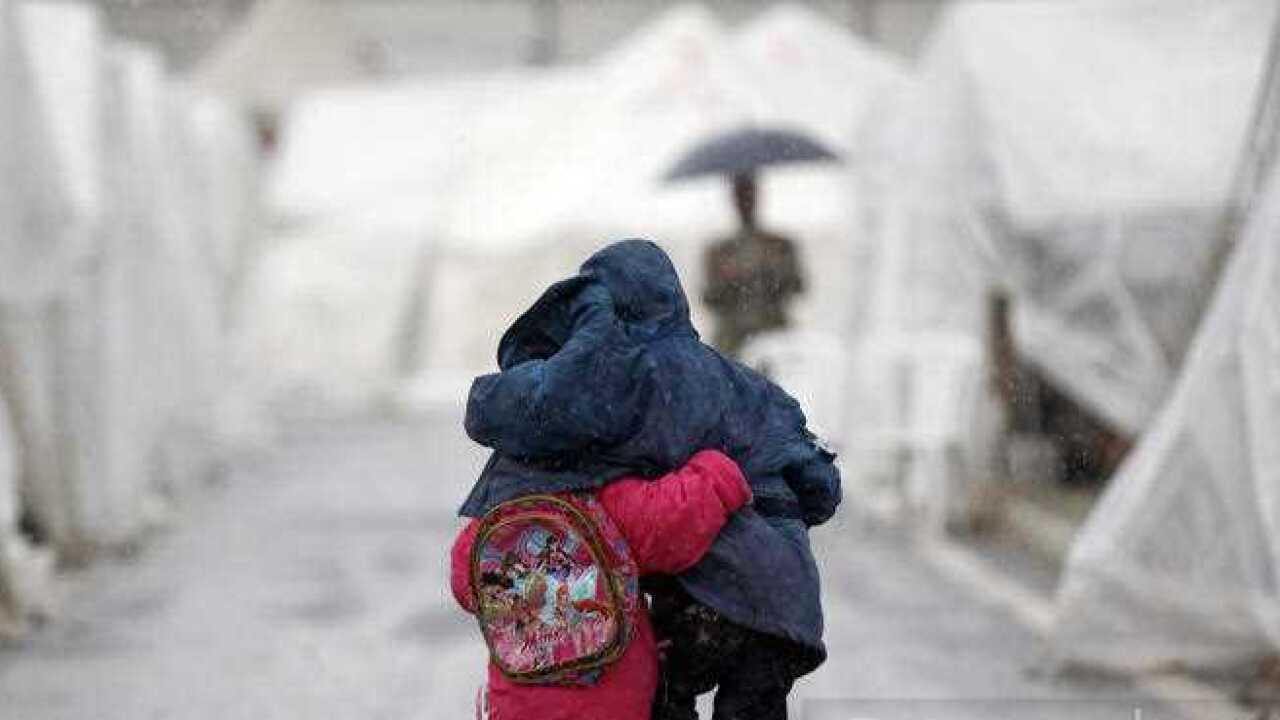 Hatay'da Türkiye-Suriye sınırındaki Boynuyoğun mülteci kampında Suriyeli çocuklar yağmurda omuz omuza yürüyor.