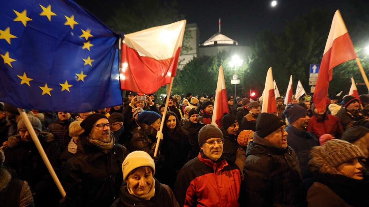 People gather to demonstrate outside the Parliament building in Warsaw, Poland, on Friday Dec. 16,