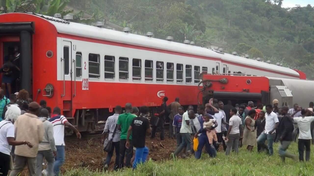 People walk beside a derailed train carriage after an accident in Eseka, Cameroon.