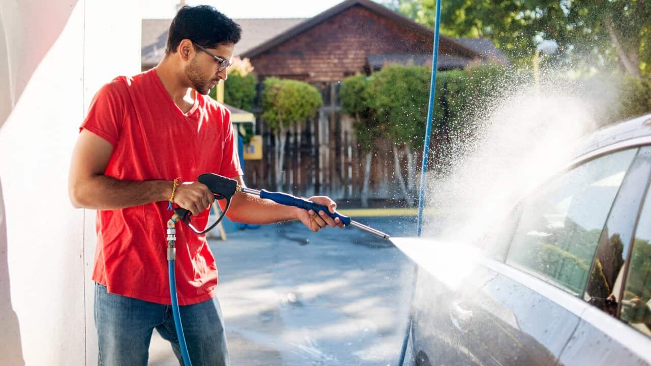 Man washing car in garage on sunny day