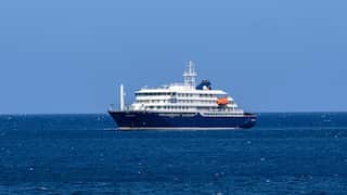 A small cruise ship with a blue hull out at a sea