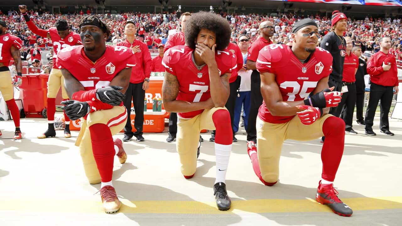 San Francisco 49ers Colin Kaepernick (C), Eli Harold (L), and Eric Reid (R) take a knee during the US national anthem before a game on 2 October 2016