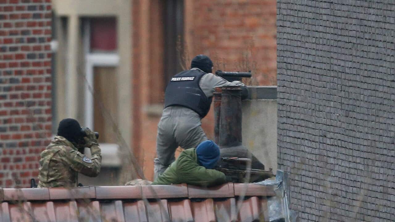 Police officers take up position on a roof during a police operation in Forest, Brussels, Belgium, 15 March 2016.