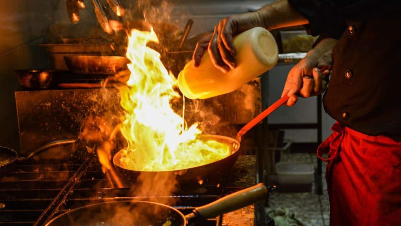 A chef executing a flambe in a professional kitchen