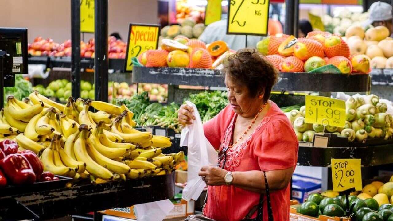 A older shopper looks at the fruit on display in a supermarket.