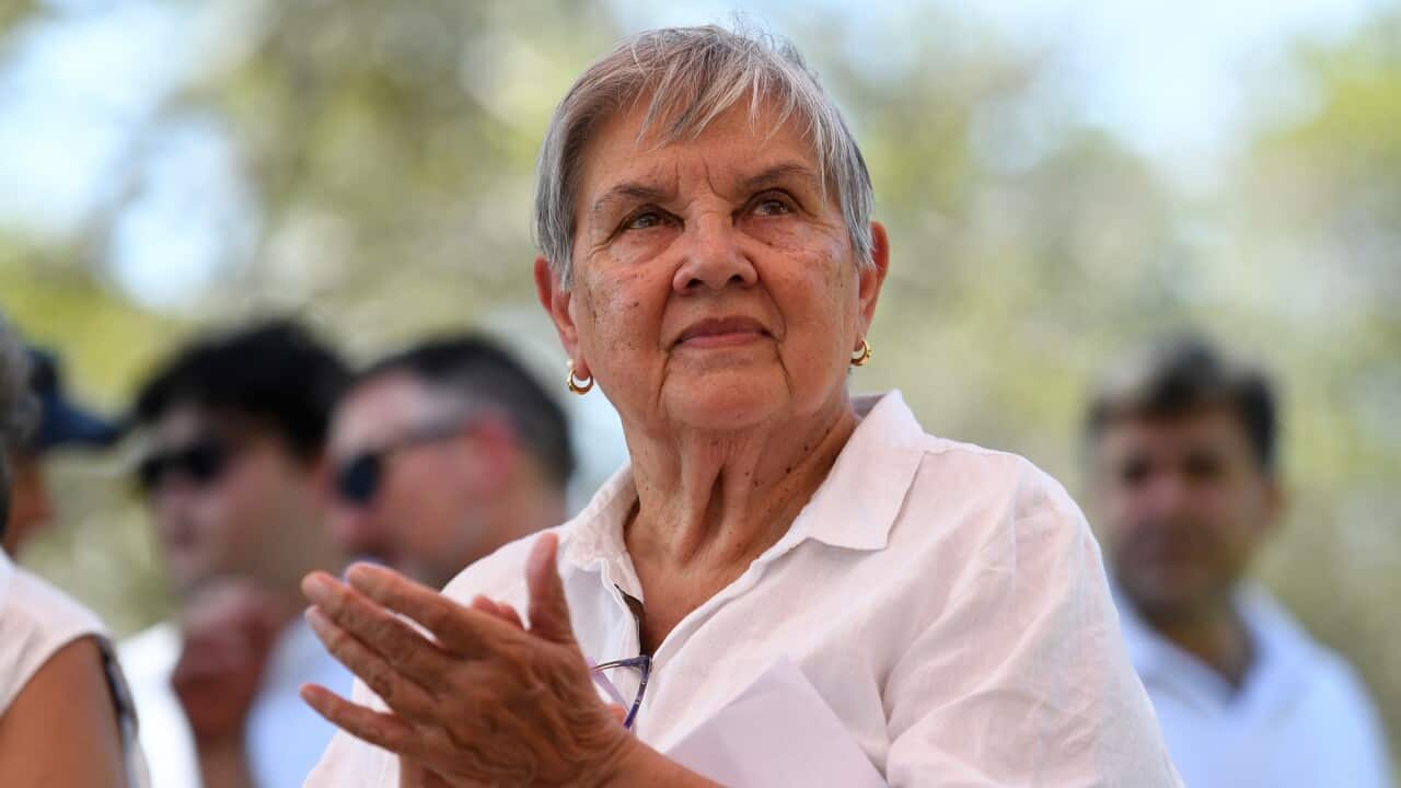Pat Anderson in a white shirt claps her hands.