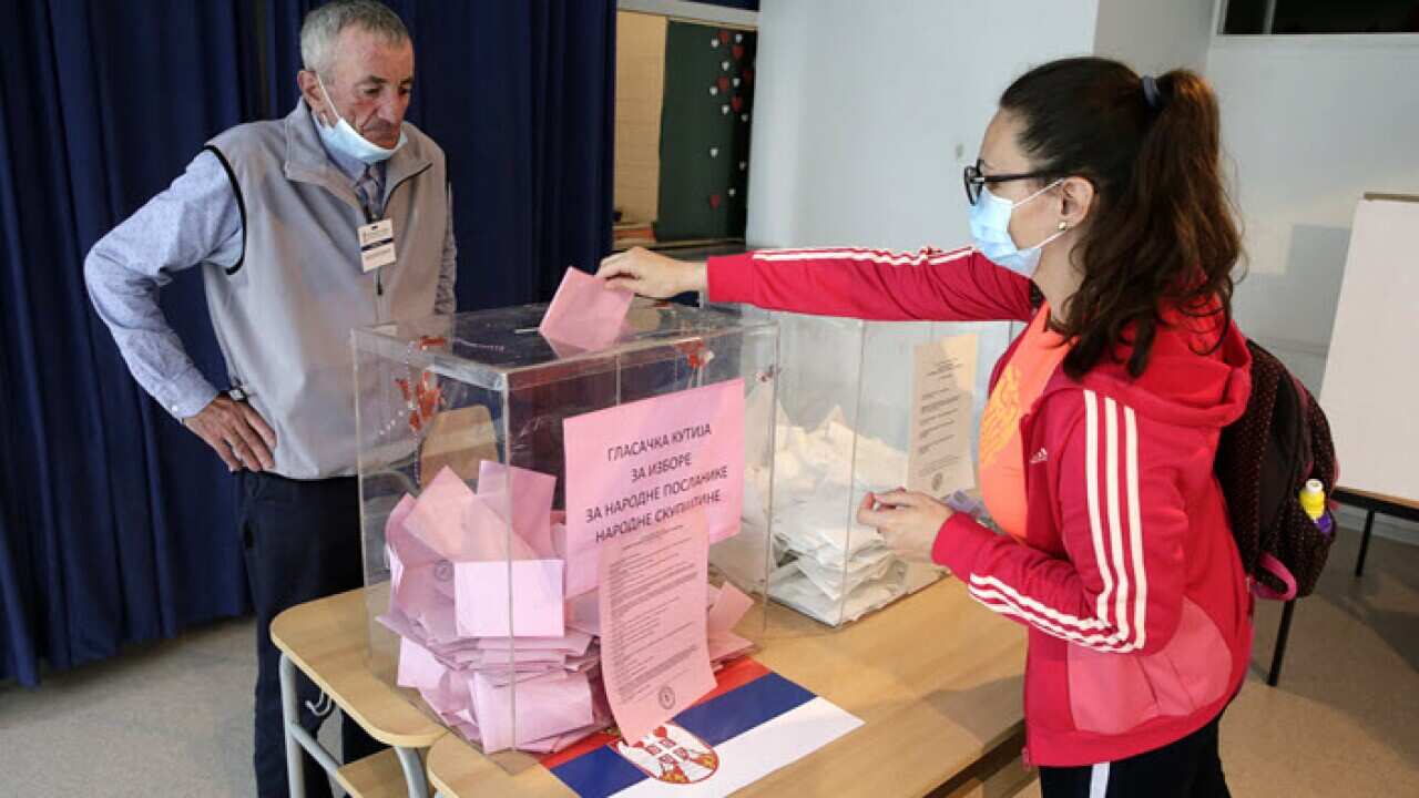 A woman wearing a protective face mask casts her ballot at a polling station in Belgrade, Serbia, 21 June 2020.